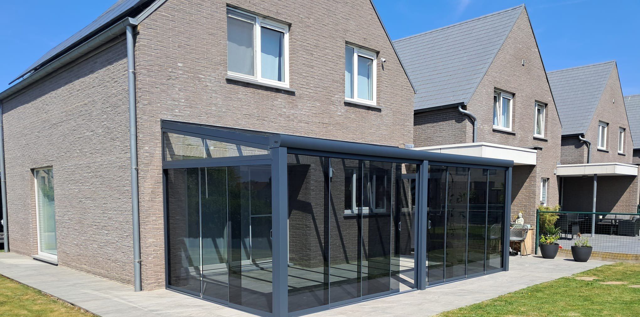 Overkapping met glazen schuifwanden rondom aan de achterkant van een woning